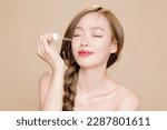 Small photo of Young Asian woman long hair braid with natural makeup on face and clean fresh skin using dropper to apply serum on isolated beige background. Female model in studio. Facial treatment, Cosmetology.