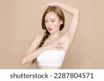 Small photo of Young Asian woman long hair braid with natural makeup on face and clean fresh skin show her armpits on isolated beige background. Cute female model in studio. Facial treatment, Cosmetology.