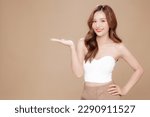 Small photo of Young Asian beauty woman curly long hair with korean makeup style on face and perfect skin show copy space on her hand on isolated beige background. Facial treatment, Cosmetology, plastic surgery.