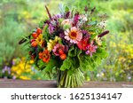 Colorful hand-tied bouquet of fresh garden flowers, herbs, scented geraniums, and rose hips