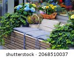 Flower arrangement with potted plants of hydrangea, ivy and heather at the entrance to flower shop in European city. Cozy seating area with cushions. Selective focus