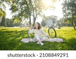 A young girl sitting on the grass and having fun making bubbles