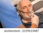 Small photo of Experienced nurse conducting an oxygenation procedure on a bedridden man