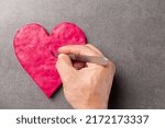 Man's hand cuts a heart with a scalpel. Cardiac surgery, heart surgery.The concept of shattered love, betrayal, human indifference and cruelty.