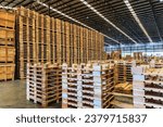 Explore the organized chaos of a bustling warehouse, where towering stacks of wooden pallets are meticulously arranged, ready for transportation and logistics