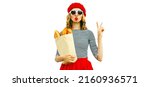 Small photo of Portrait of beautiful woman blowing her red lips sending sweet air kiss holding grocery shopping paper bag with long white bread baguette wearing french red beret isolated on white background