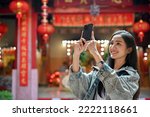 Close up view of young woman taking a photo with smartphone while traveling in Asian traditional temple