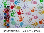 Small photo of Colorful hand prints with paints and watercolor on white paper. Imprints of little child during fun, sensory play and education in kindergarten. Many hands in different color. Top view.