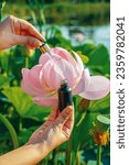 Small photo of Oil with lotus flower extract. Essence on the background of lotus flowers. Dark opaque glass bottle. Essence for moisturizing the face. Anti age oil