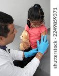 Small photo of Dark-haired Latino doctor and little girl have a medical consultation in the pediatric office to vaccinate their arm against Covid, chickenpox, diphtheria, influenza, hepatitis, measles, mumps