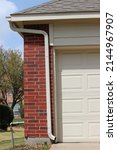 Small photo of Roof gutters and a downspout next to garage door on a residential house