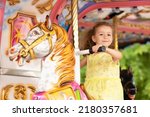 Adorable little toddler girl on carousel horse. child on attraction. kid entertainment. Happy healthy baby having fun outdoor on sunny day. Family weekend, vacations, holiday. 