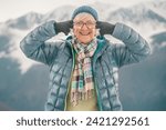 Joyful senior woman in outdoors in winter time looking at camera pointing her fingers at the eyes saying look at me