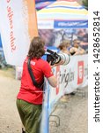 Small photo of A man in a red Canon shirt taking pictures with super telephoto lens. The lens is Canon 400mm.