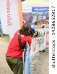 Small photo of A man in a red Canon shirt taking pictures with super telephoto lens. The lens is Canon 400mm.