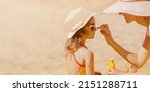 Small photo of Mom carefully smears her child's face with protective cream on the beach. Skin care. Protection from the sun. Sunscreen for children.