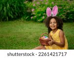 Little Black girl wtfring bunny ears gathering Easter eggs