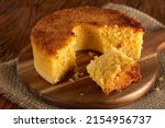 Small photo of Homemade round cake made of green corn and cheese, known as "Pamonha Cake". Typical Brazilian food of Festa Junina(june festival) with a piece cut on a round wooden board on a rustic wooden table.