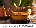 Small photo of Homemade round cake made of green corn and cheese, known as "Pamonha Cake". Typical Brazilian food of Festa Junina(june festival) with a piece cut on a round wooden board on a rustic wooden table.