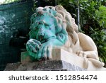 Vandalized statue of a sad lion. Sad green colored face with spray paint