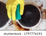hand in household glove cleaning grease and dirt from kitchen stove