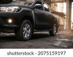 Small photo of YEKATERINBURG, RUSSIA - APRIL 30, 2020: A black Toyota Hilux against an impressive urban landscape at sunset. Wet road. Shagreen car coating. Trends in the automotive industry.