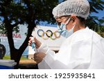 Small photo of Apucarana, Parana, Brazil - February 17, 2021 - Health professional prepares syringe with coronavirus vaccine (COVID-19) in the Apucarana sports gymnasium, at the background of the Olympics.