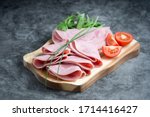 Fresh pork ham slices on cutting board over dark background