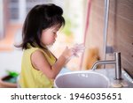 Small photo of Cute Asian girl washed her hands with soap in the white sink. Children rub the bubbles in her hands intently. Side view of kids was cleaning her palms to wash away the dirt. Child is 3-4 years old.