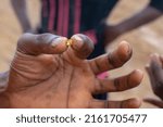 Small photo of KUNSU, GHANA – May 22, 2022: Ghanaian Illegal miner finds a small nugget of gold. Ghana gold nugget.
