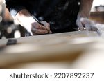 Small photo of Busy and serious joiner holding yellow sander and working with wood. Professional carpenter in safety glasses standing in joiner's shop. Concept of woodworking and craftsmanship.