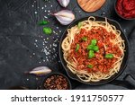Culinary background with pasta and tomato sauce and fresh herbs on a black concrete background. The concept of cooking.