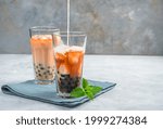 Bubble tea, making a Taiwanese drink with tapioca, milk and ice on a gray background. Side view. A refreshing, healthy drink.