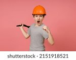 Small photo of combat screaming boy in a gray t-shirt with a helmet on his head brandishes a big funnel and shows his fist, pink background