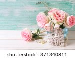 Pink roses flowers  in blue vase  and decorative heart on white painted wooden background against turquoise wall. Selective focus. Place for text.