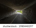 A dark bike underpass with a curve in the end of the tunnel.