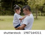 Hispanic dad hugging his little daughter in the park-father and daughter outdoors smiling face to face