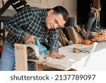 Small photo of Happy carpenter working with carpentry tools - Smiling Hispanic man doing carpentry in a wood workshop - Man in his carpentry