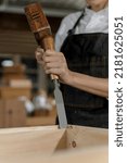 Small photo of Carpenter woman holding hammer and punching on chisel with wood working in carpentry shop, close up gouge wood chisel carpenter tool in hands hammering wood frame in carpentry project