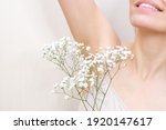 Young woman holding her hands up and showing armpits with gypsophila in her hand, armpits smooth transparent skin. The girl shows a clean armpit. Beauty portrait. Hair removal and depilation.