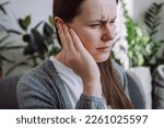 Small photo of Closeup up side profile of sick young caucasian female having ear pain touching painful head sitting on sofa. Unhealthy woman 20s suffering from painful otitis. Health care and tinnitus concept