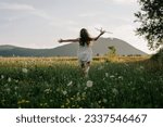 Small photo of Back view of preteen girl in dress playing with violet toy airplane during beautiful warm sunset. Childhood dreams. Family, nature, freedom and airplane concept. Playful cute little child pilot