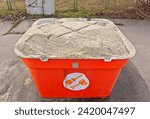 Small photo of Grit salt bin. Container with rock salt mixture used in cold season to sprinkle sidewalks, ice melt, slippery prevention. Salt container close up, salt for slippery surface. Melting snow and ice.
