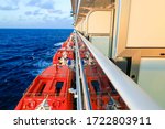 Small photo of Side of cruise ship with lifeboats and balcony staterooms in the sea
