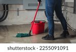 Small photo of Woman mopping flood from water leaks in basement or electrical room. Water damage from rain, snowmelt or pipe burst coming from multiple cracks and leaks in concrete wall and ceiling. Selective focus.