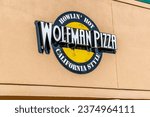 Small photo of Charlotte, NC USA - May 11, 2023: Horizontal, medium, oblique shot of "Wolfman Pizza" outdoor exterior facade brand and logo signage on a bright sunny day.