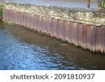 Small photo of Riverside metal sheet pilings with stone top and flowing water Huddersfield Yorkshire England 16-12-2021 by Roy Hinchliffe