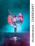 Small photo of Cold gin and tonic under pink and blue light illumination on smoky background with copy space. Vertical format.