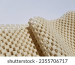 Small photo of Light yellow, rubberized, mesh, anti-slip carpet underlay - on a white background, with diagonal fold (macro, texture).