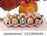 Small photo of Eggs with different faces in eggbox and and a Orpington Hen, Rooster as advertising. Types of temperaments. Sanguine, choleric, angry, phlegmatic, happy or melancholic. Face illustrated on eggs